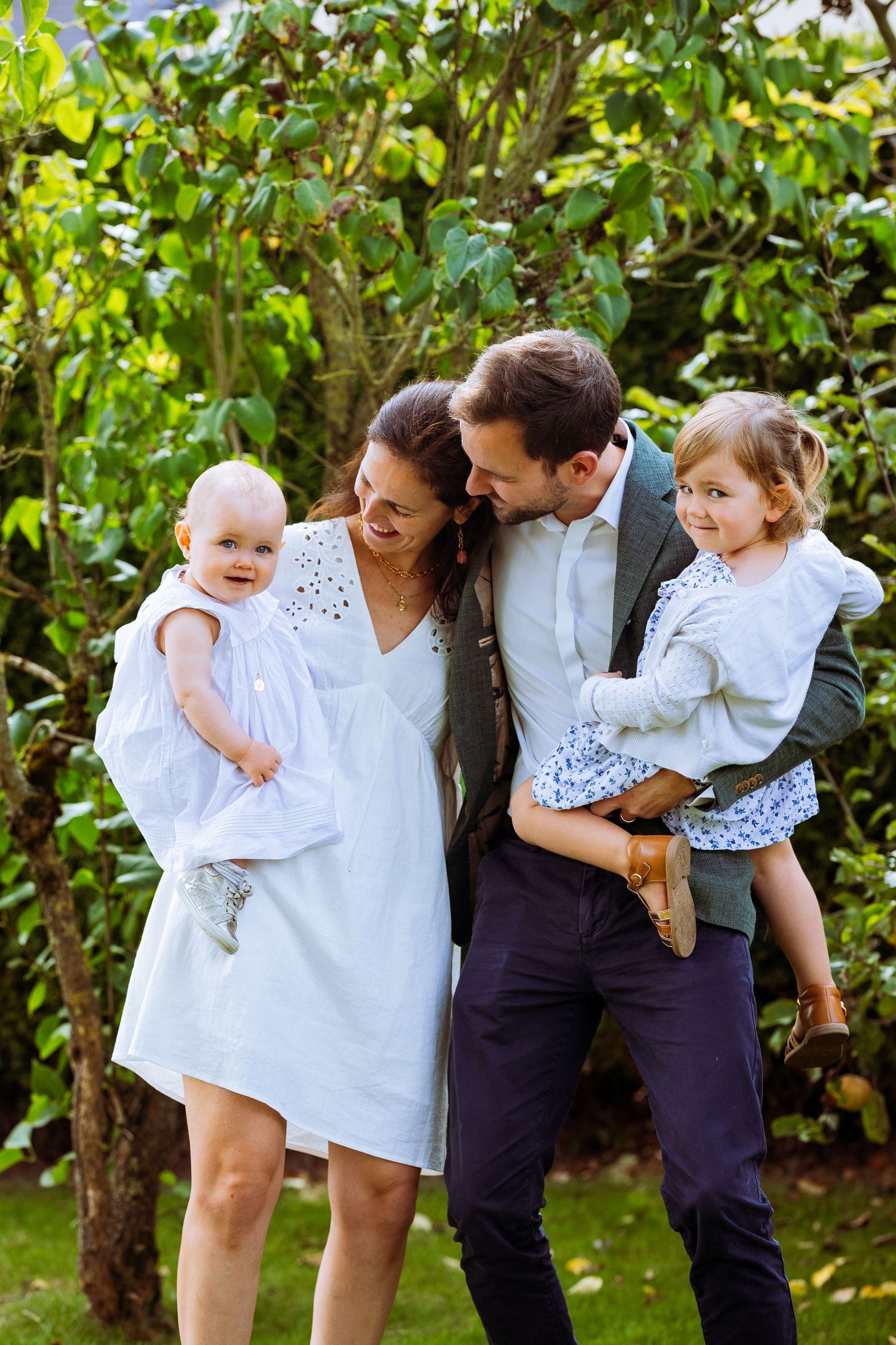 A group enjoys playful moments together in a garden setting wearing coordinated white and navy outfits.