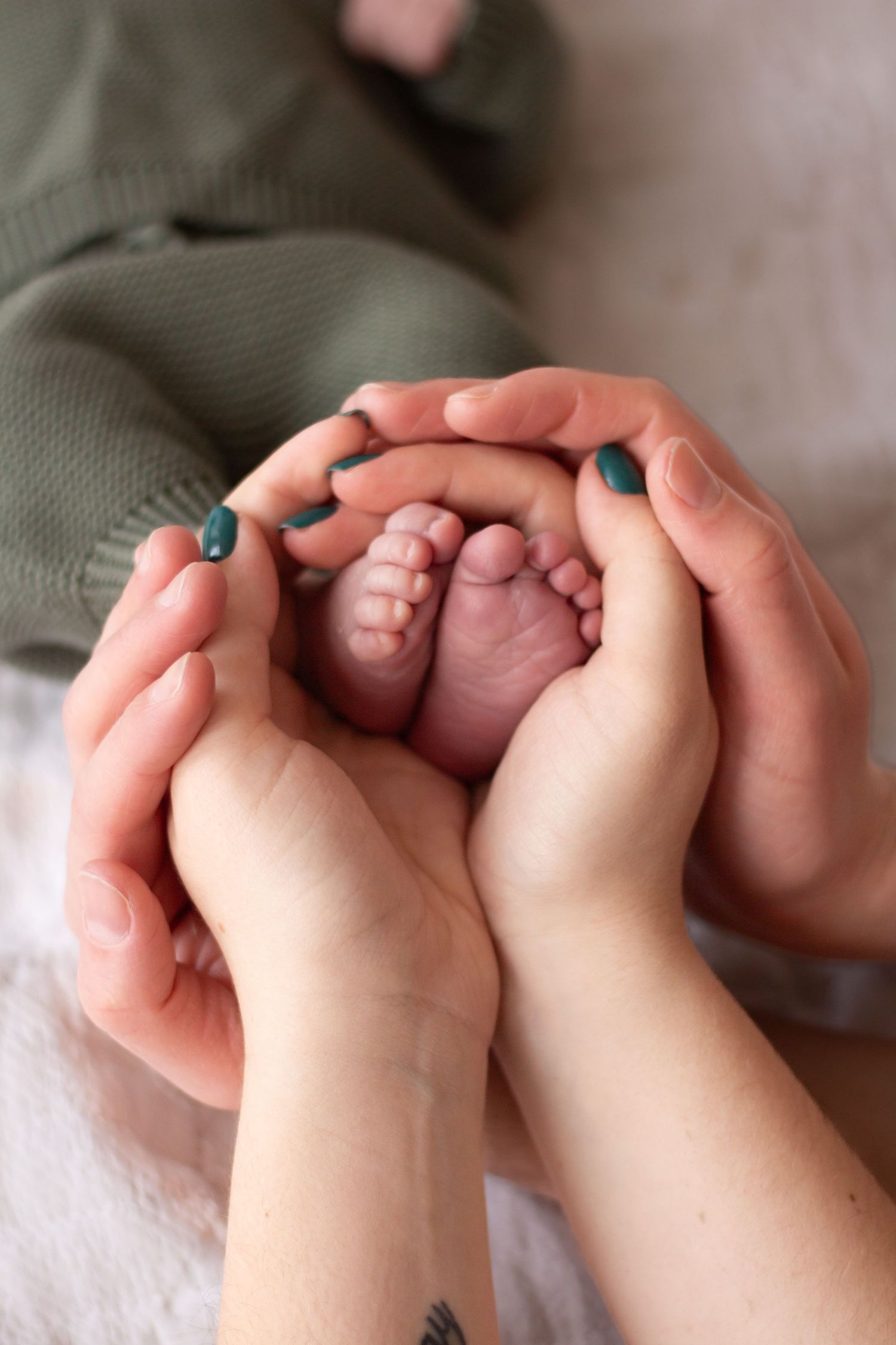 Close-up series of tiny baby feet with teal painted toenails being gently held by caring hands.