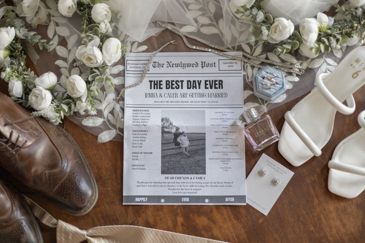 Wedding details including a custom newspaper, brown leather shoes, white sandals, and floral arrangements on wooden surface.