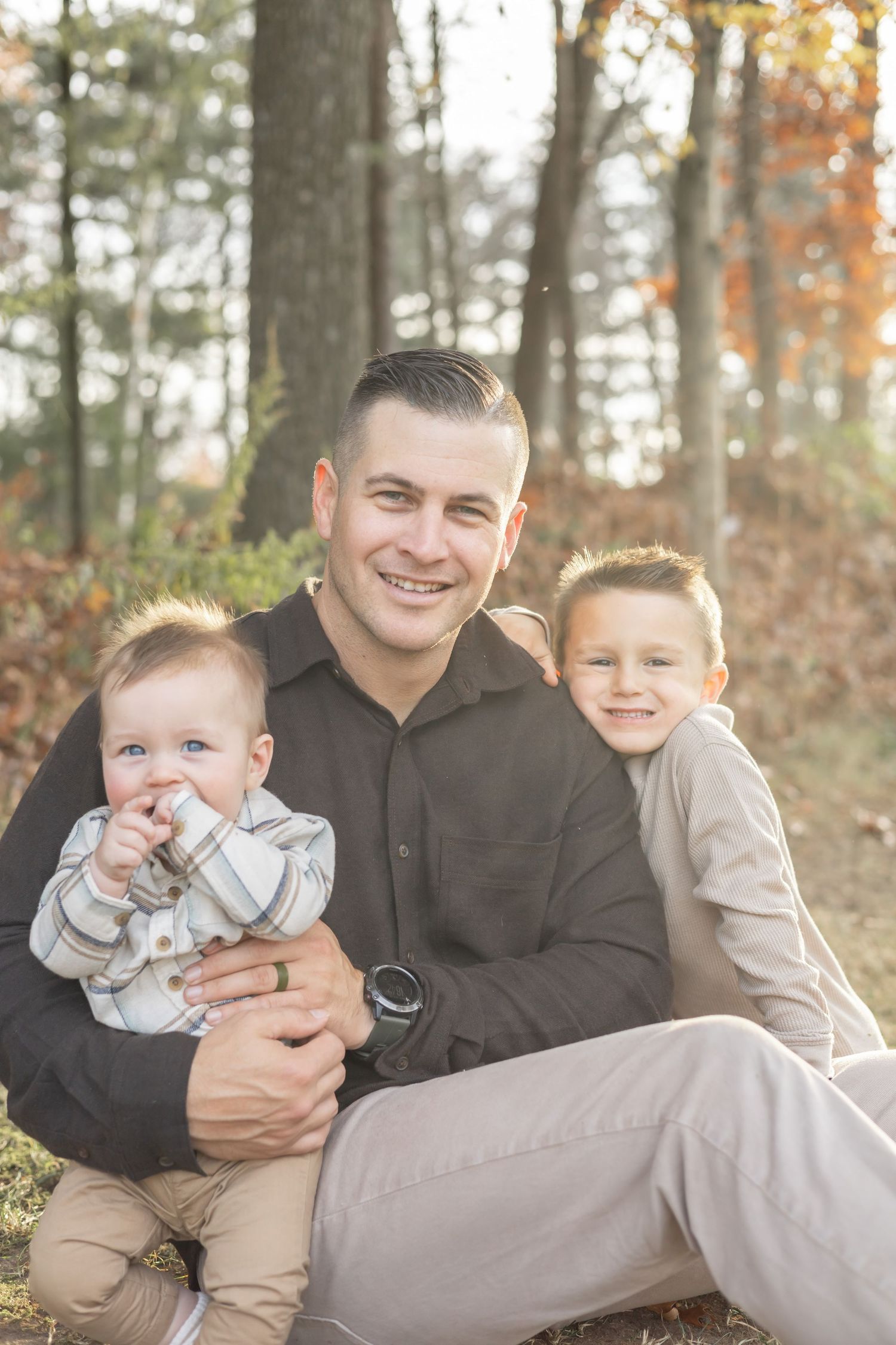 A family photo shoot in a wooded setting during autumn showcases heartwarming candid moments.