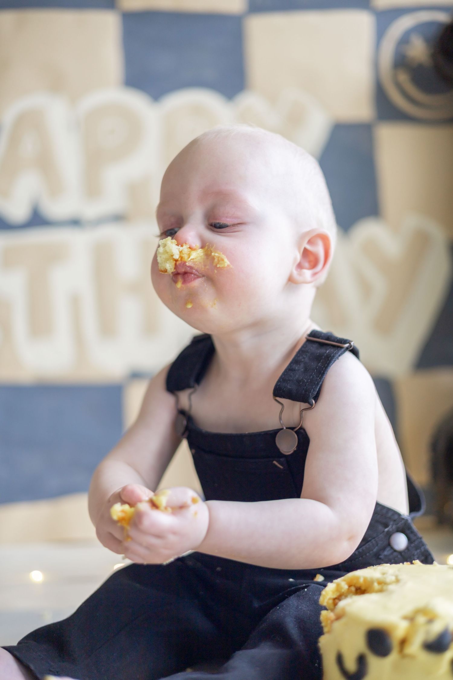 Infant wearing black dress sits with french fries while eating and making a mess during a meal.
