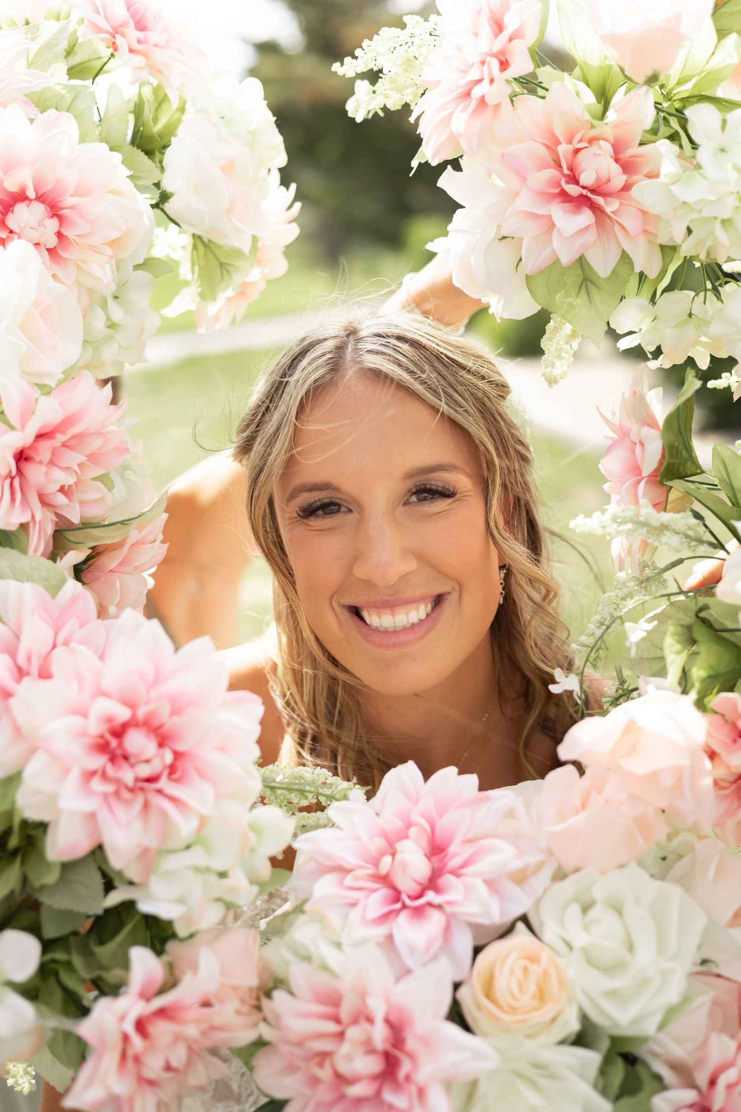 Delicate pink and white floral crown arrangement featuring carnations and roses with soft natural lighting.