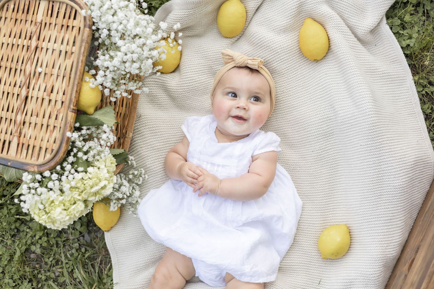 A white wicker basket sets a rustic scene with fresh lemons and delicate white flowers on natural linen.