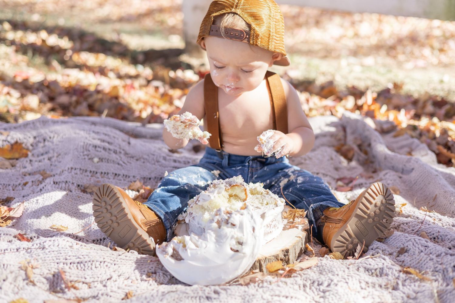 A boho-inspired picnic setup on sand with blankets, candles, cushions and crystal glasses creating a romantic ambiance.