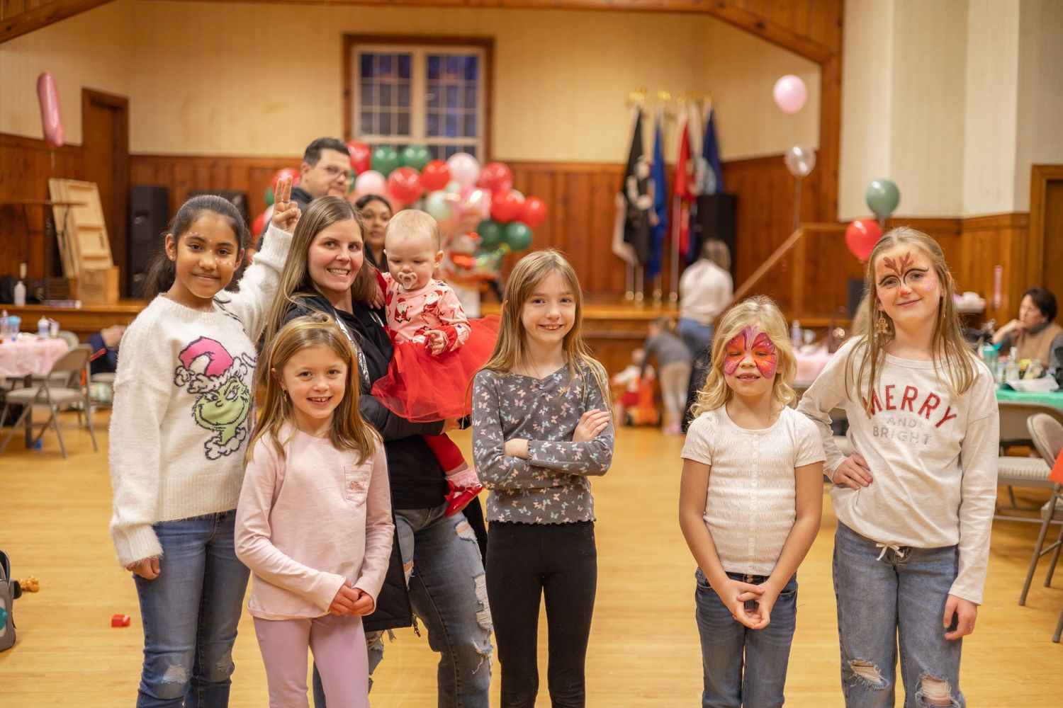 A group of children lined up in a gymnasium during what appears to be a holiday celebration.