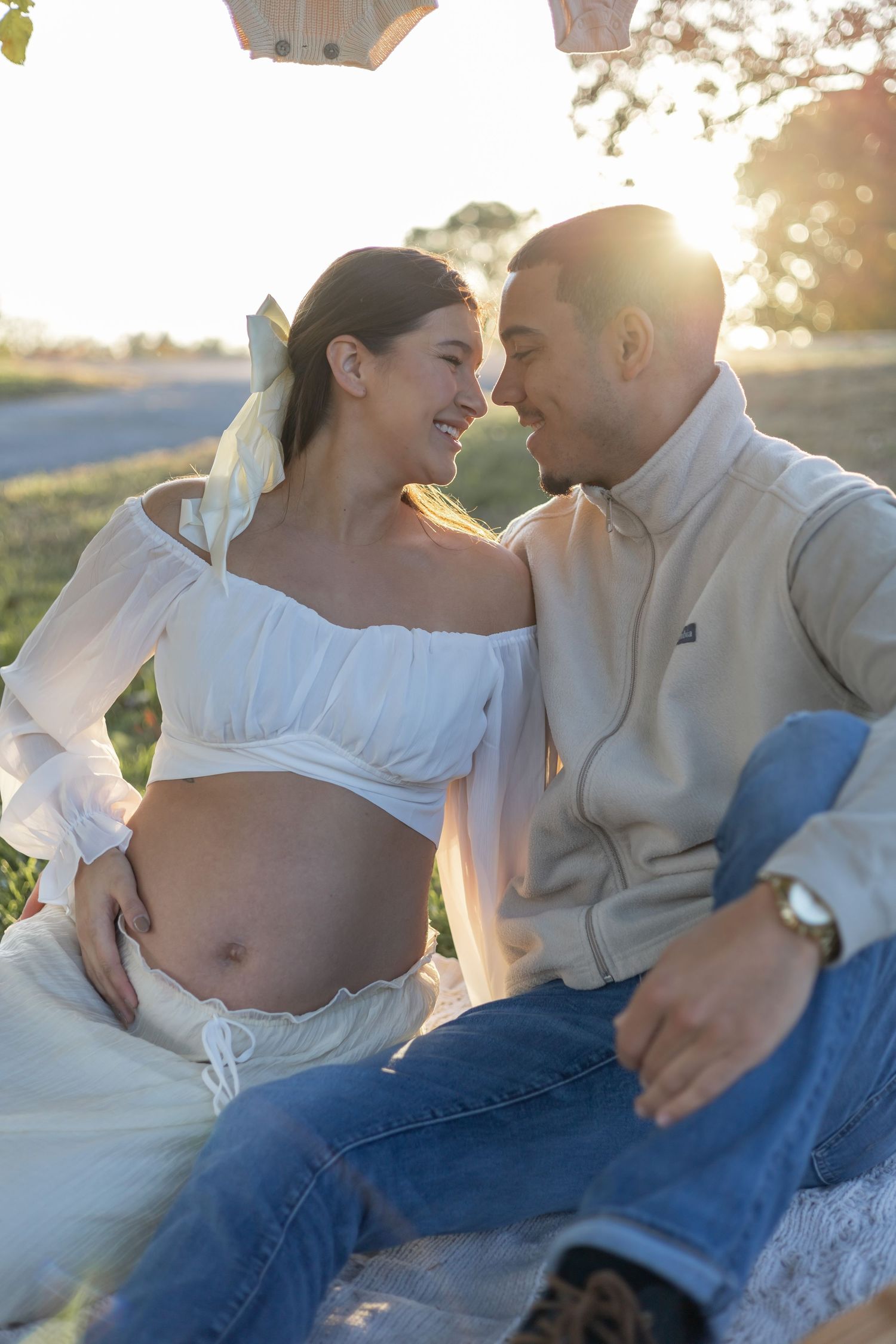 Romantic maternity photography session featuring couple in casual attire lounging outdoors.