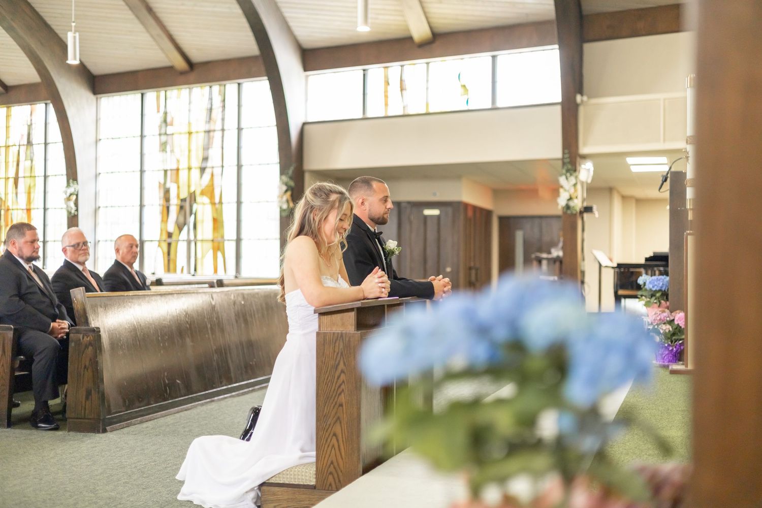Newly married couple walking down a hallway with guests seated and applauding their grand entrance.