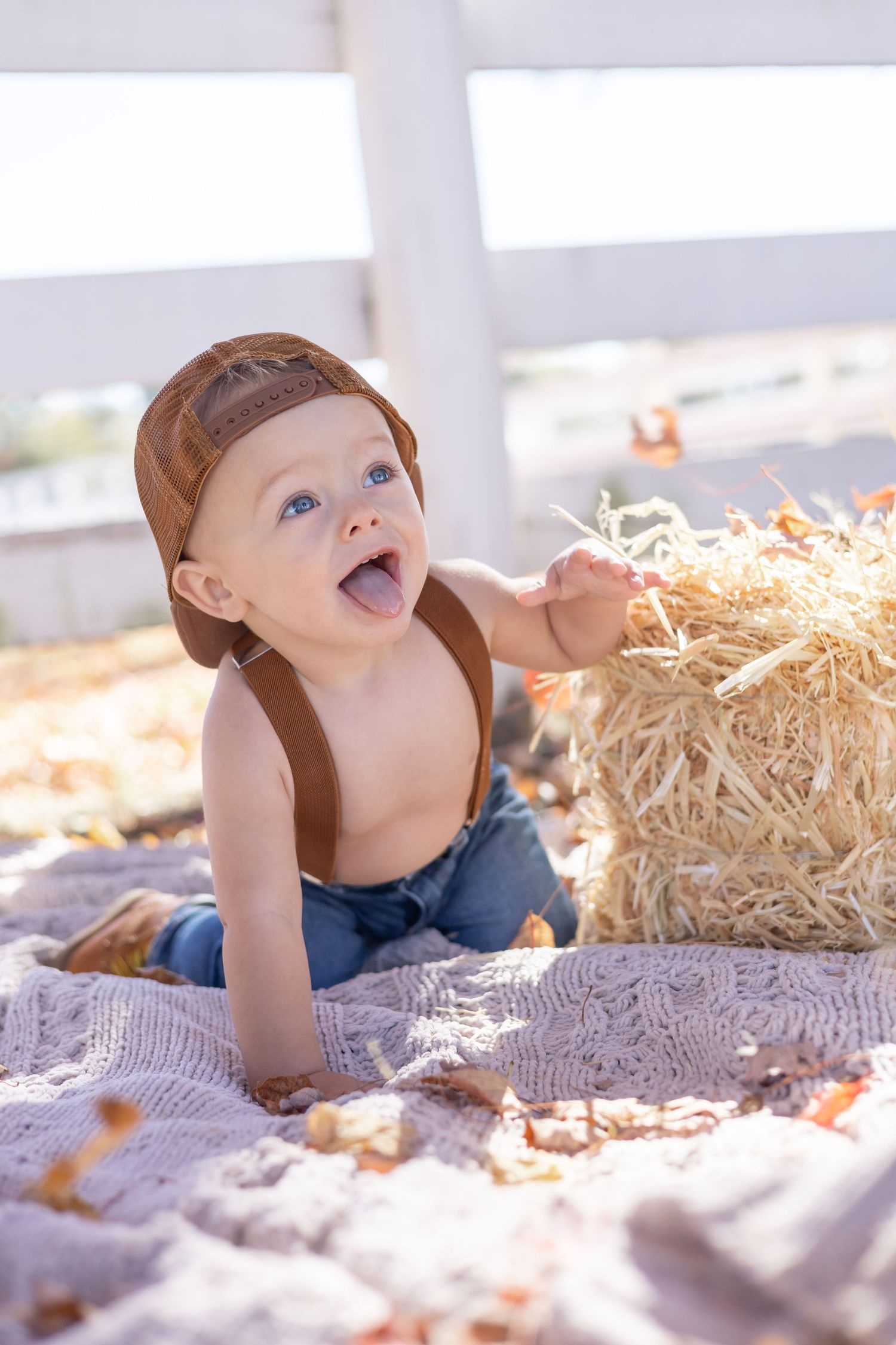 Young child lying on blanket next to hay bales enjoying an autumn day outside.