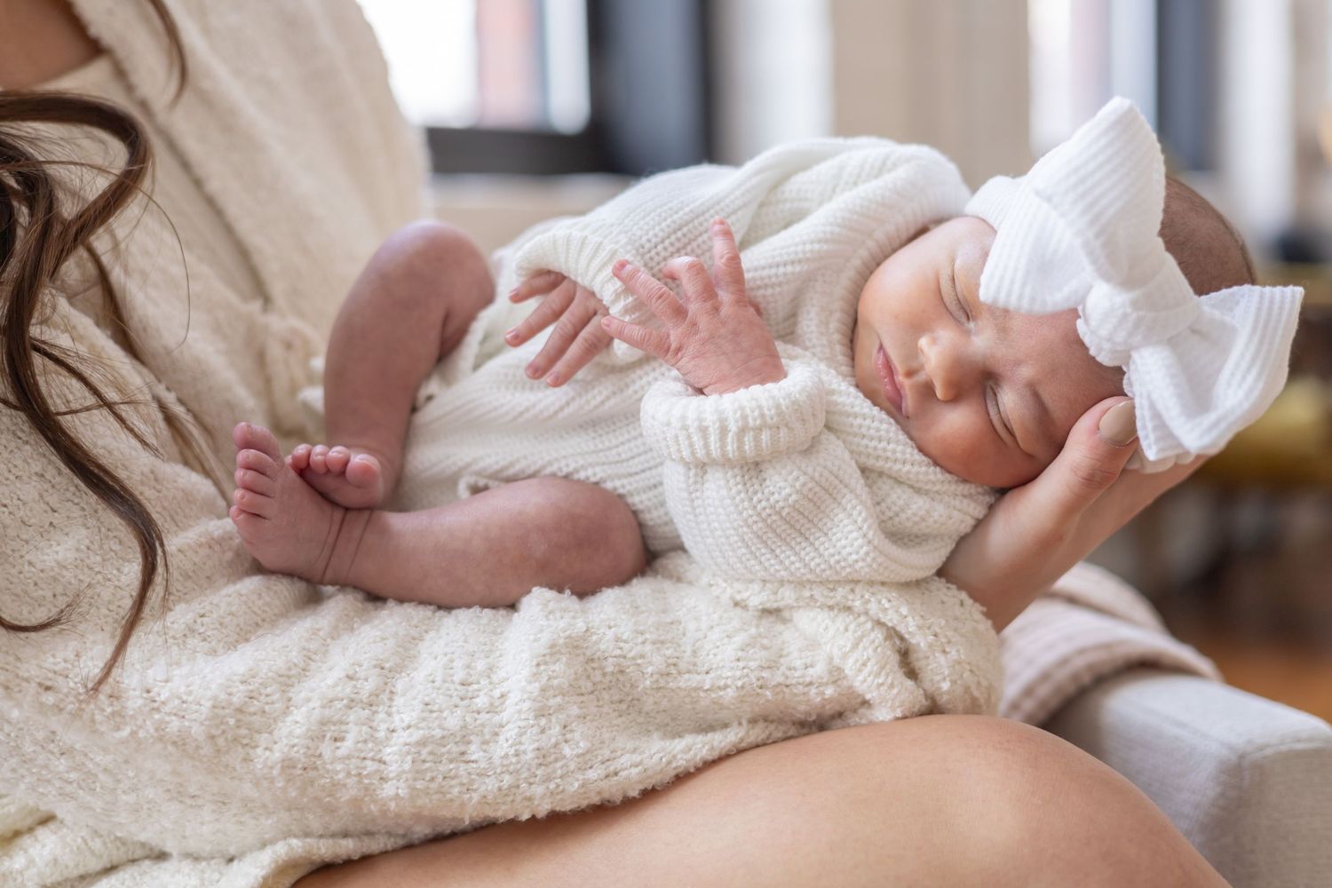 A white knitted baby outfit lies flat on a wooden floor with different close-up details shown across multiple images.
