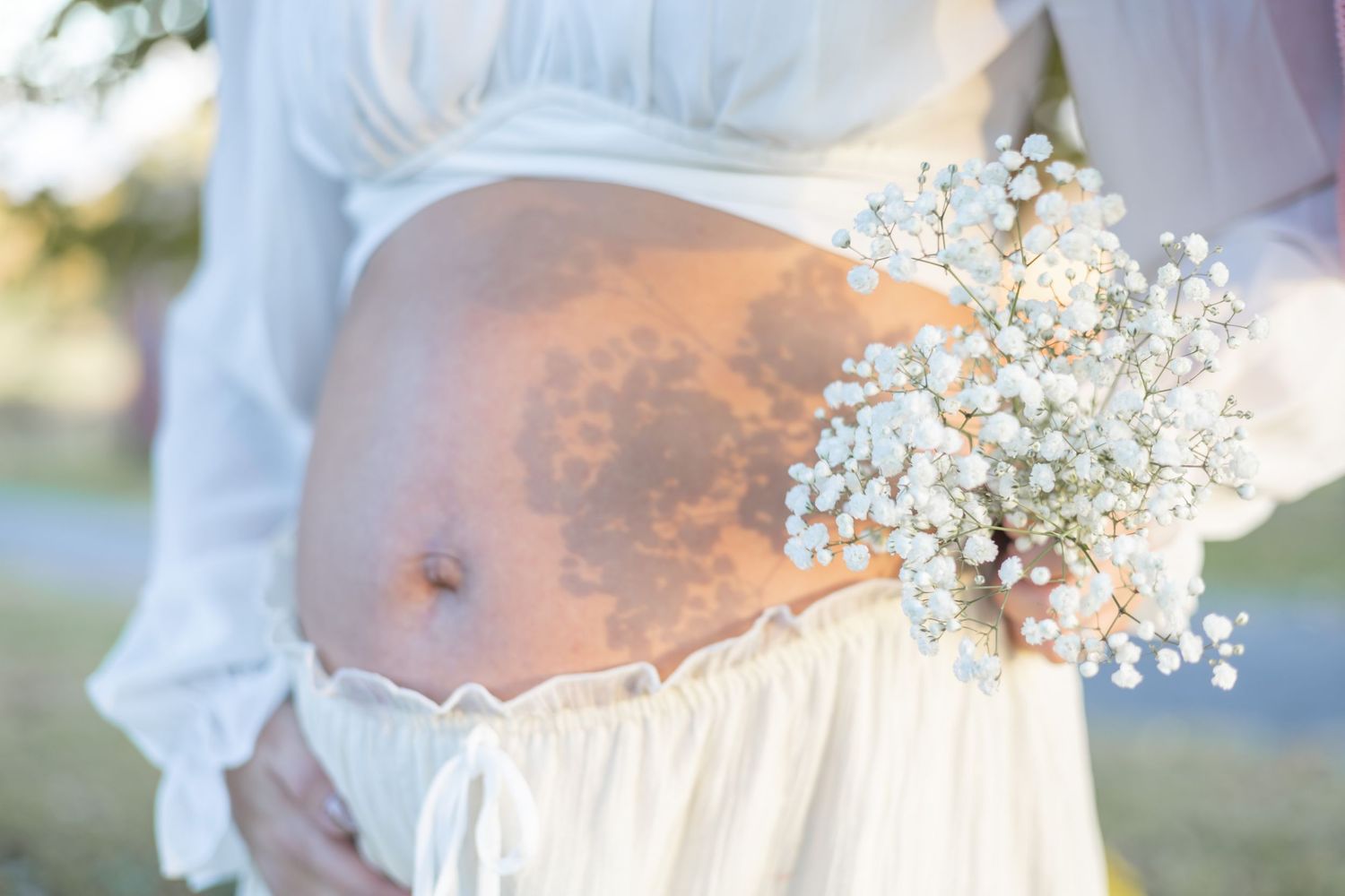 Delicate white baby's breath flowers add a soft touch to maternity photography session.