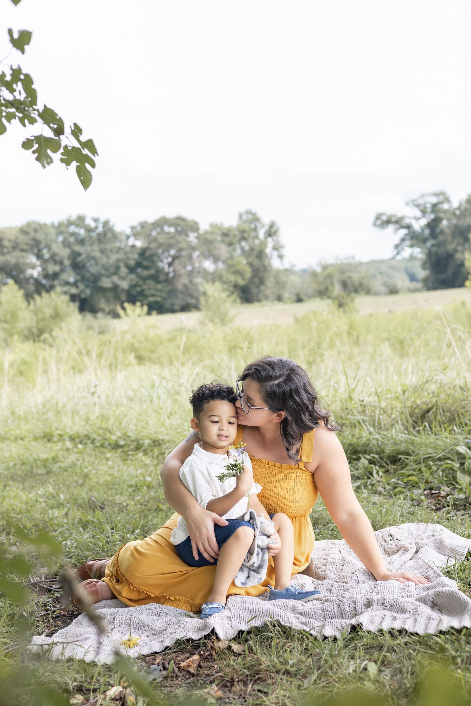 Peaceful afternoon scene of two people sitting together on a blanket in a serene meadow setting.