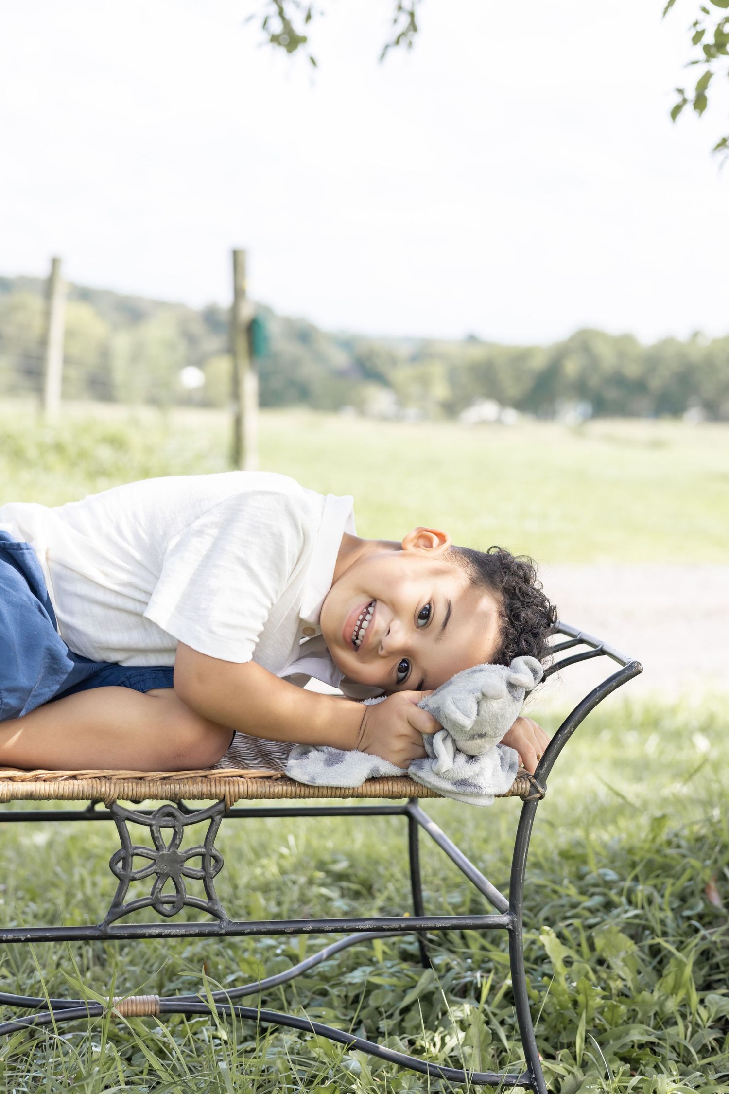 A child lying on a rustic wooden bench outdoors while enjoying a relaxing moment in nature.