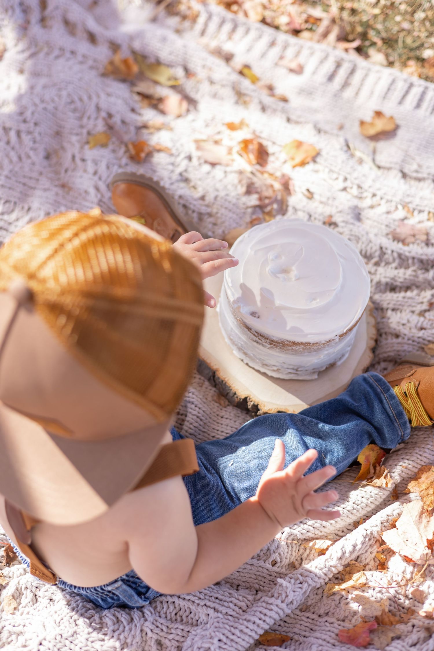 Someone sitting on a knitted blanket outdoors holds a takeaway coffee cup on a sunny autumn day.