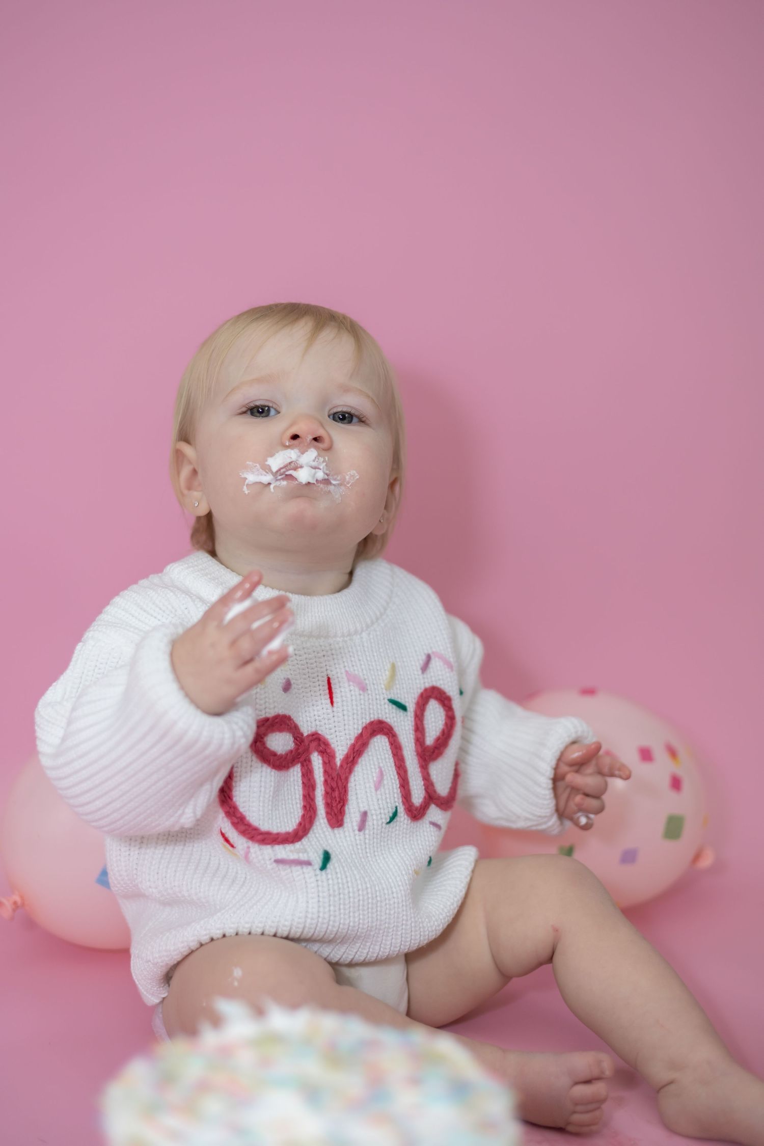 Baby wearing white bib reclining on pink background with playful expressions across multiple progressive photos.