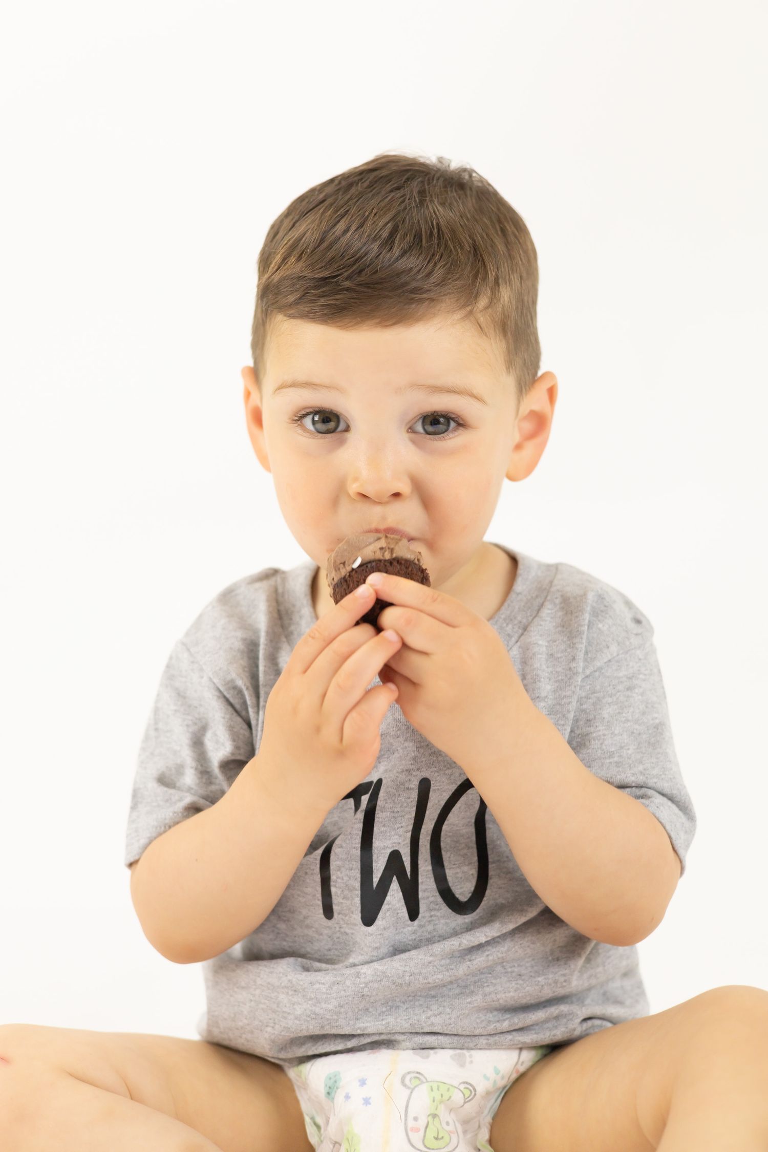 Young child in grey t-shirt covering their mouth with both hands in series of expressive poses.