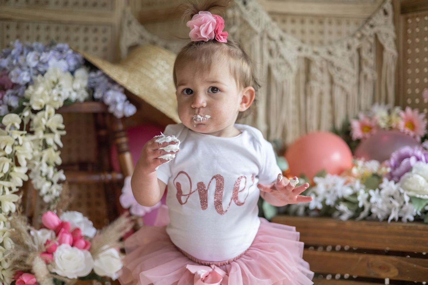 Pink tutu and birthday outfit with decorative floral backdrop and vintage furniture setting.