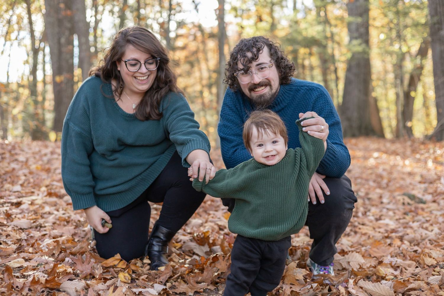 Family enjoying a playful autumn moment together in fallen leaves during golden hour at a park.
