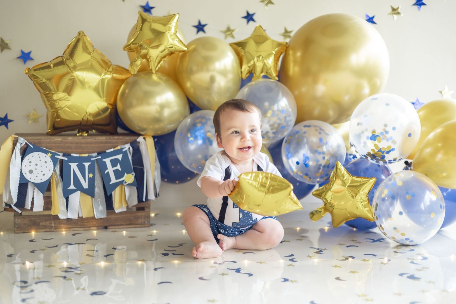 Festive gold and blue balloons with star decorations create a celebratory first birthday party setting.