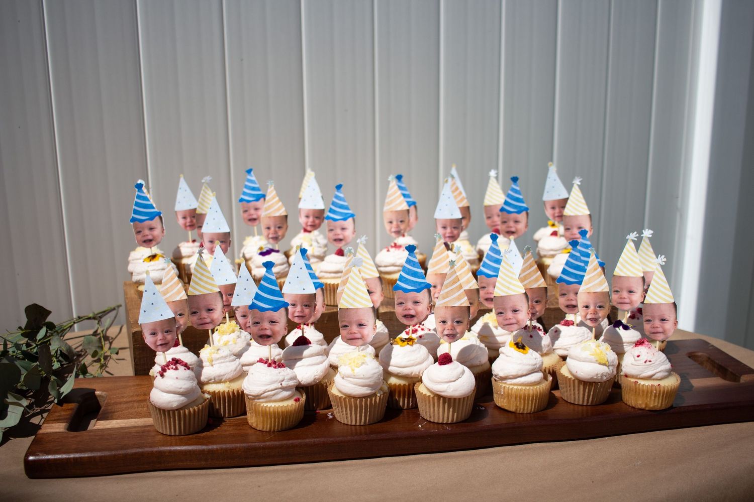 Decorated cupcakes with blue and white toppings arranged on a wooden serving board in natural lighting.