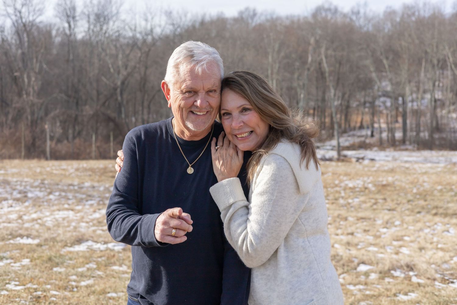 Couple enjoying a romantic moment together while walking outdoors in a winter field.