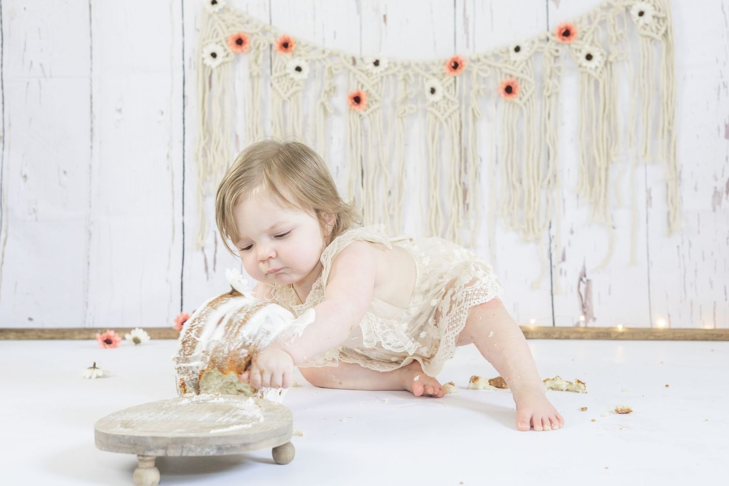 Small child reaches across rustic wooden table to explore and touch raw baking ingredients in kitchen setting.