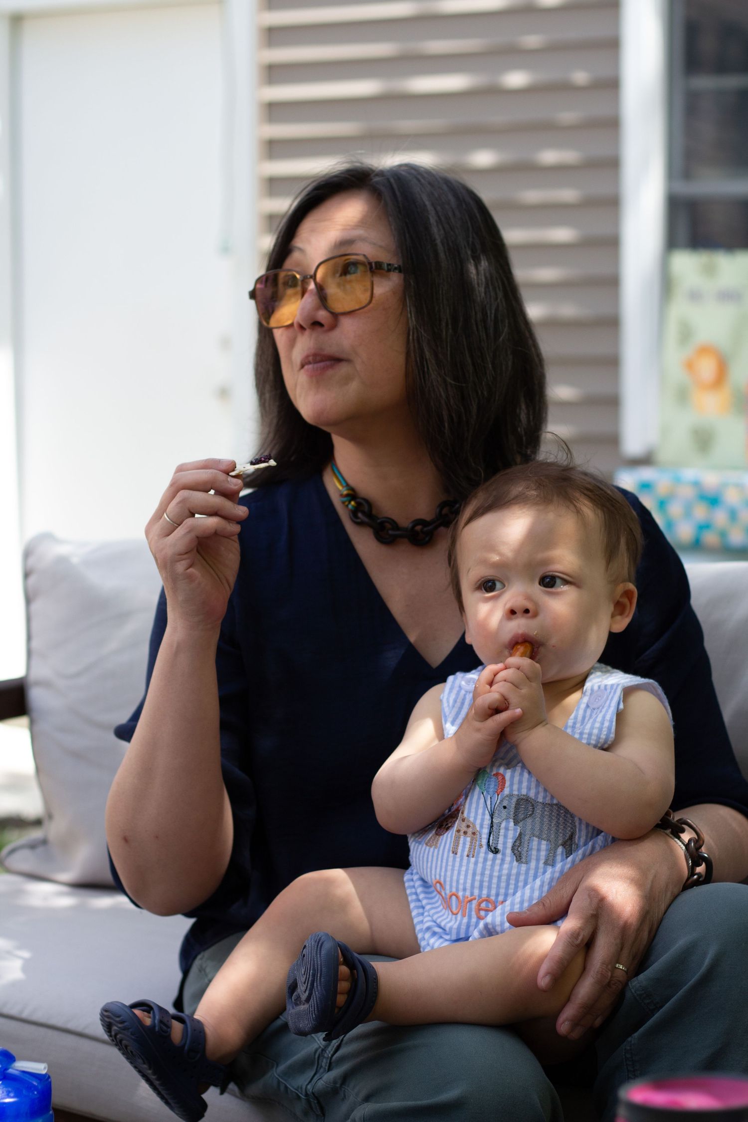 Sequence of four photos showing adult and baby sharing snacks while sitting together on couch.