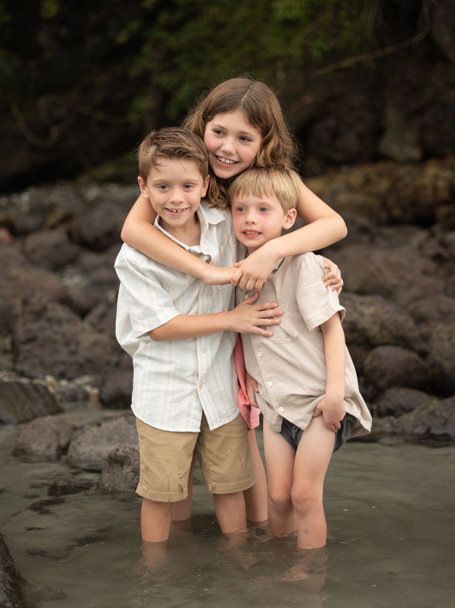 Young children playing and embracing together on a rocky beach at sunset. Manuel Antonio, Costa Rica.