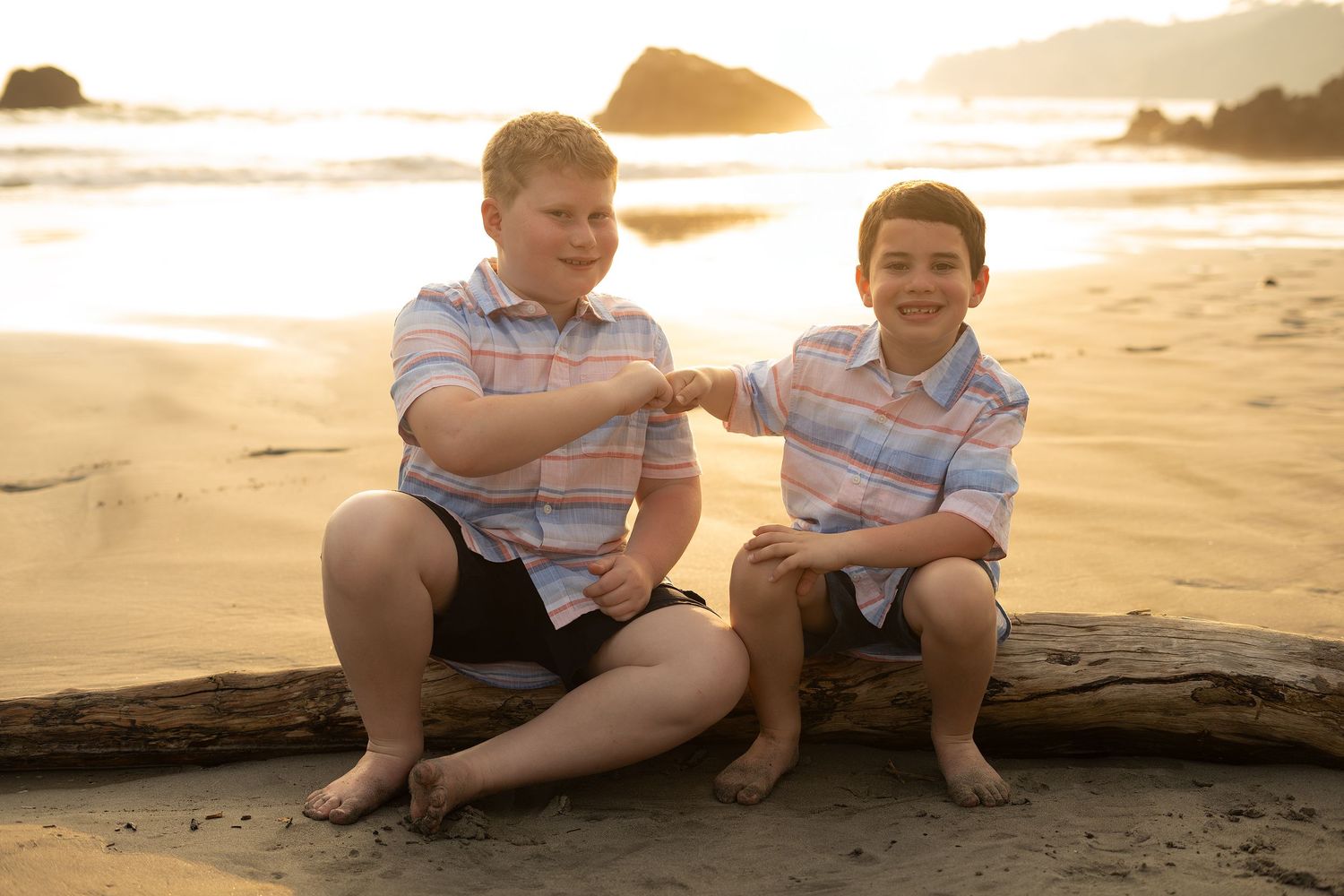 Two people sitting together on beach log during warm sunset. Manuel Antonio, Costa Rica.