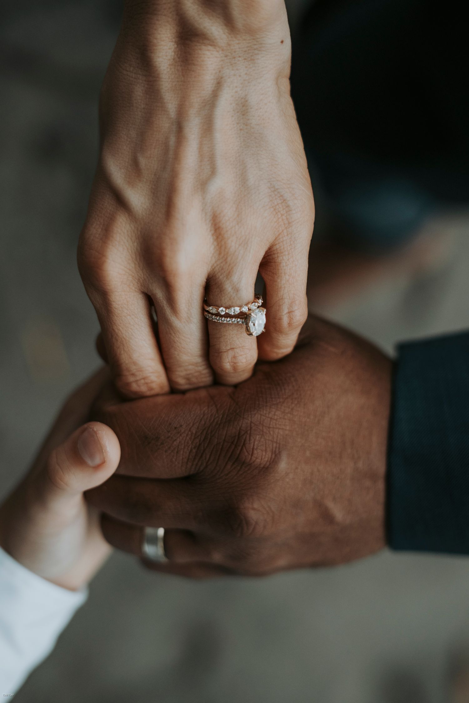 Two hands with wedding rings touch intimately in a series of close-up photographs showing interracial love and unity.