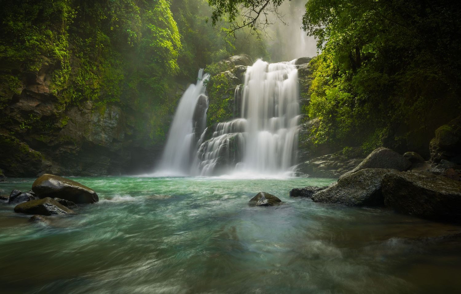 Series of cascading waterfalls flowing into turquoise pools surrounded by lush forest.