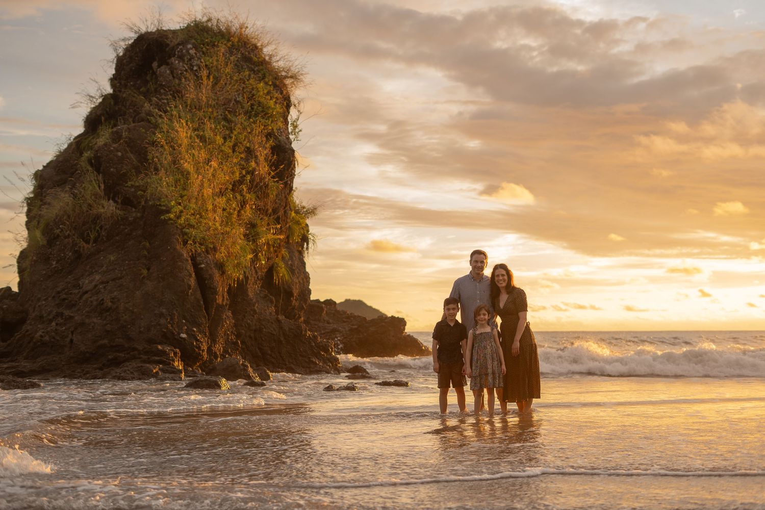 Silhouetted family portrait at sunset against dramatic coastal rock formation. Manuel Antonio, Costa Rica.