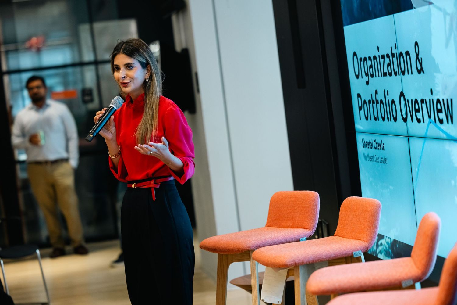 A person in a red shirt stands near blue wall displays during what appears to be a business presentation or exhibition.