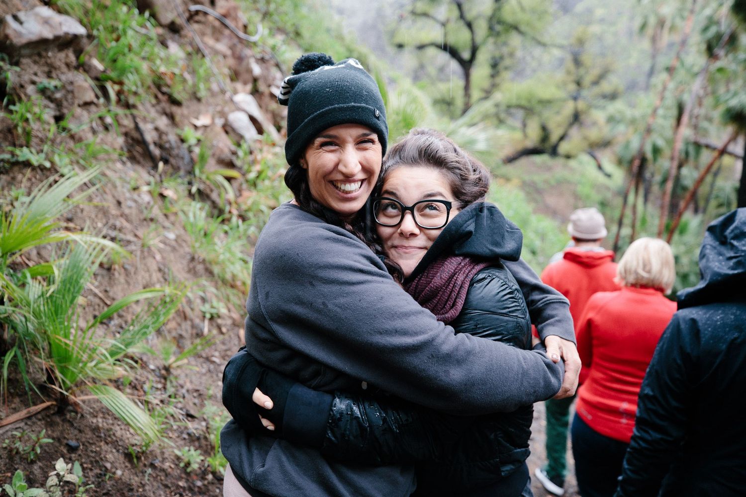 Happy people embrace and share joyful moments outdoors in a natural setting during a group gathering.