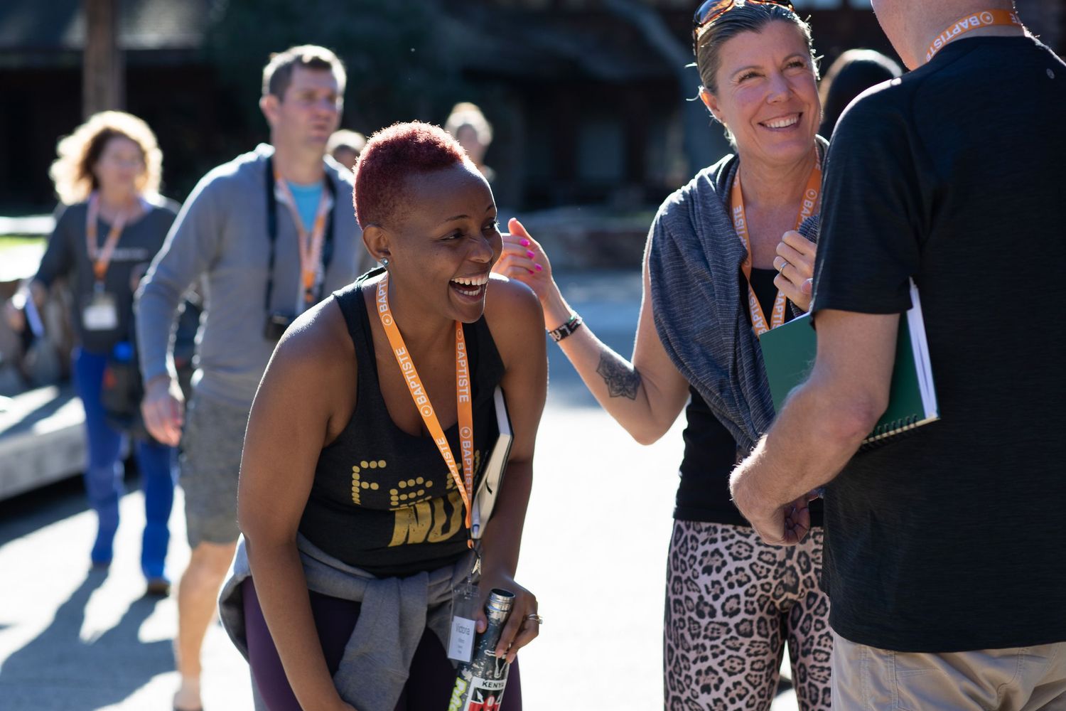 Conference attendees mingle outdoors during a sunny day networking break.