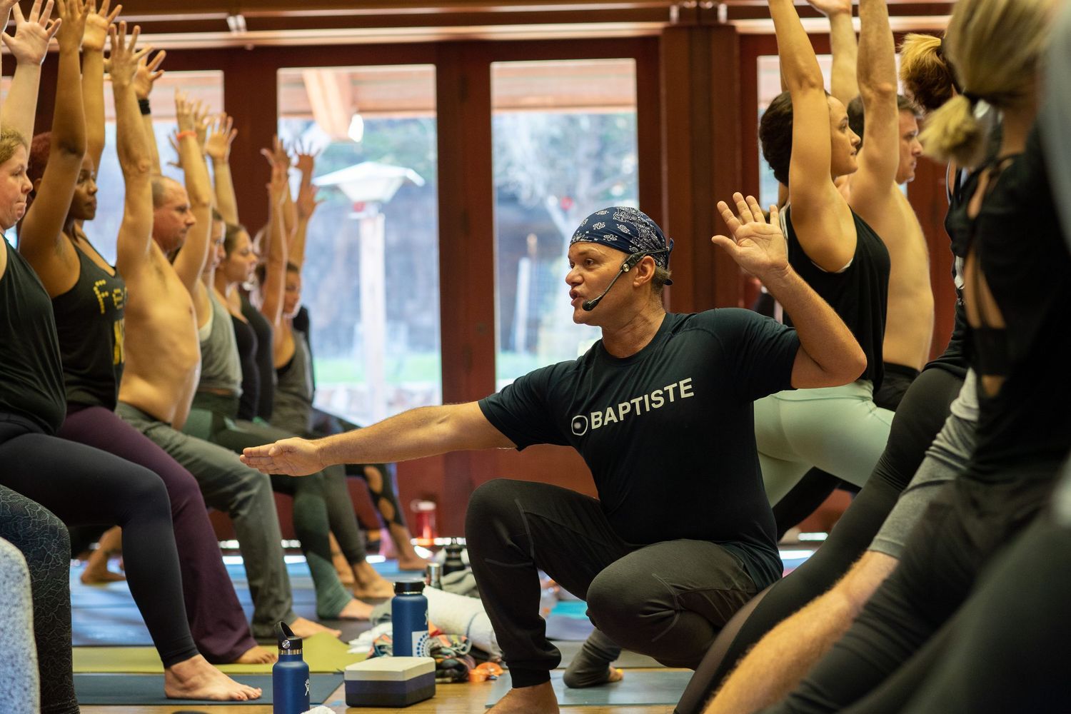 Yoga class participants raise their arms in unison during a group exercise session.