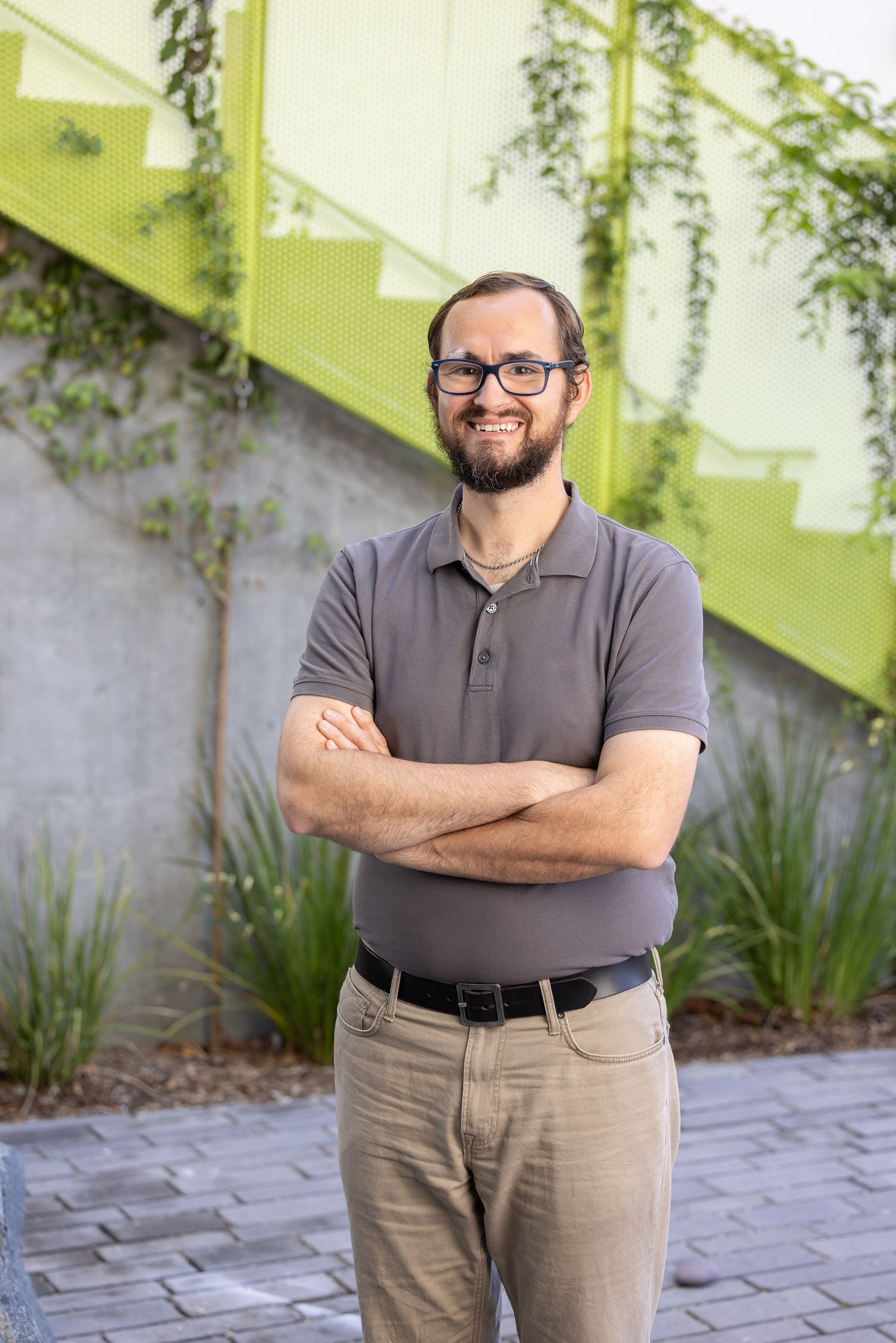 Business casual portraits showing someone in a gray polo shirt standing against a lime green wall.