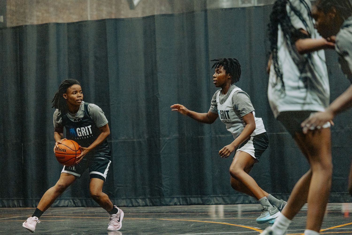 Players practicing offensive moves during indoor basketball training.