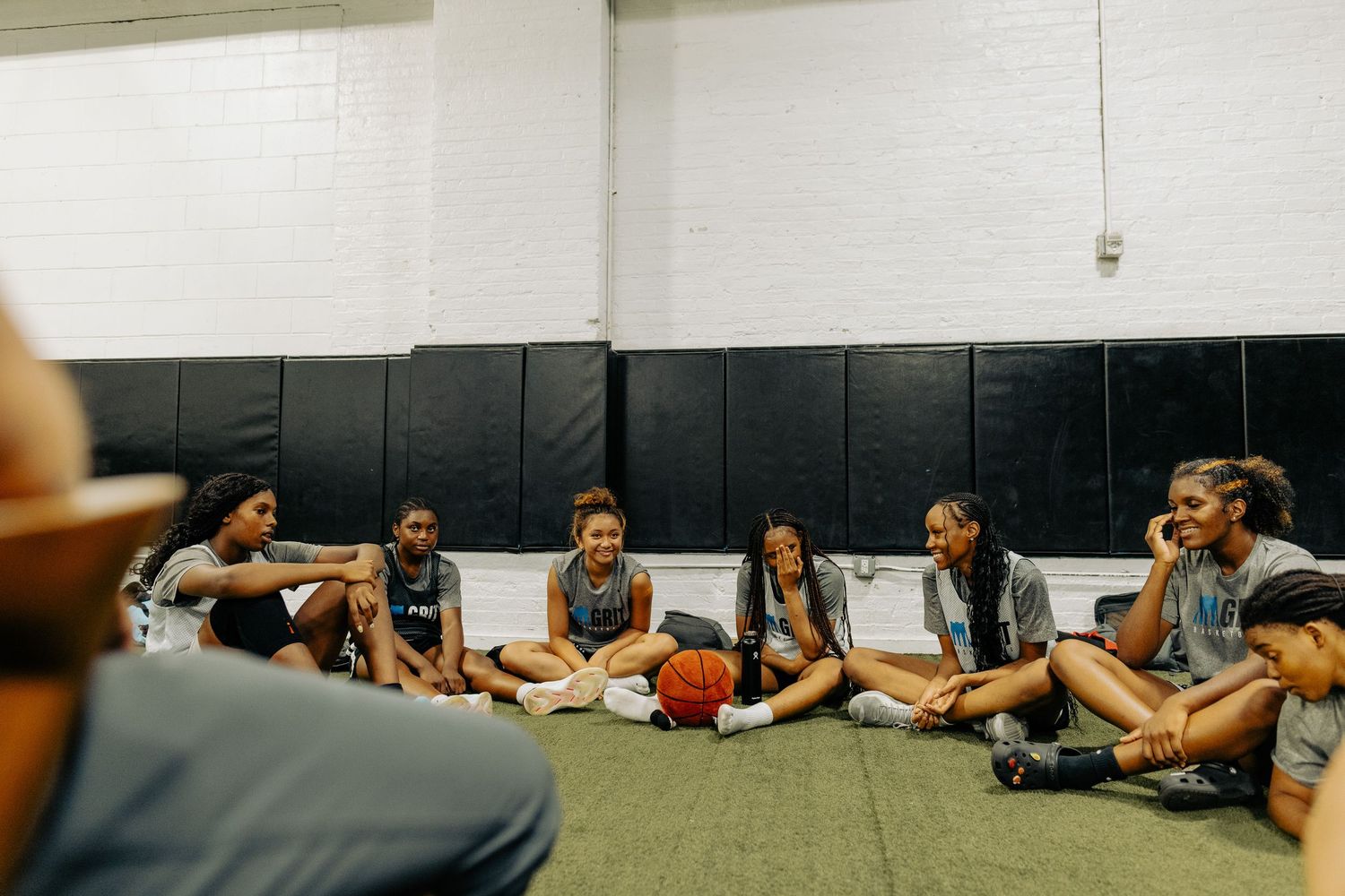 Team members stretching and resting together on gym floor mats.