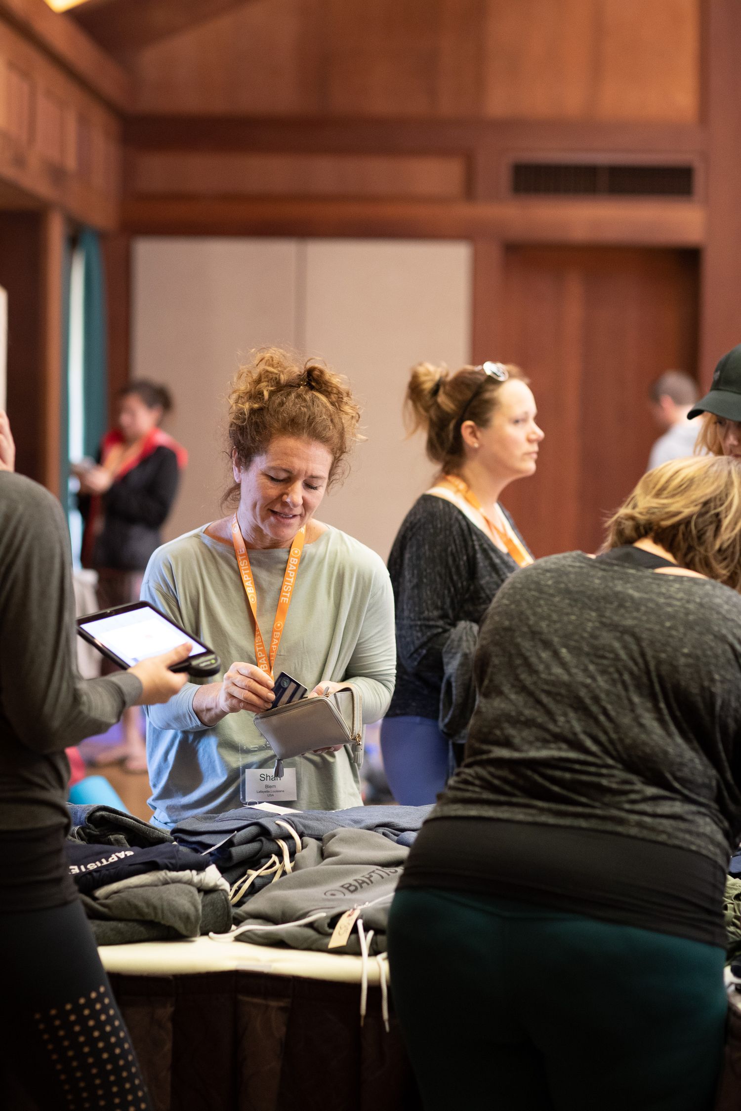 Attendees check phones and gather materials during a break at an indoor conference or workshop.