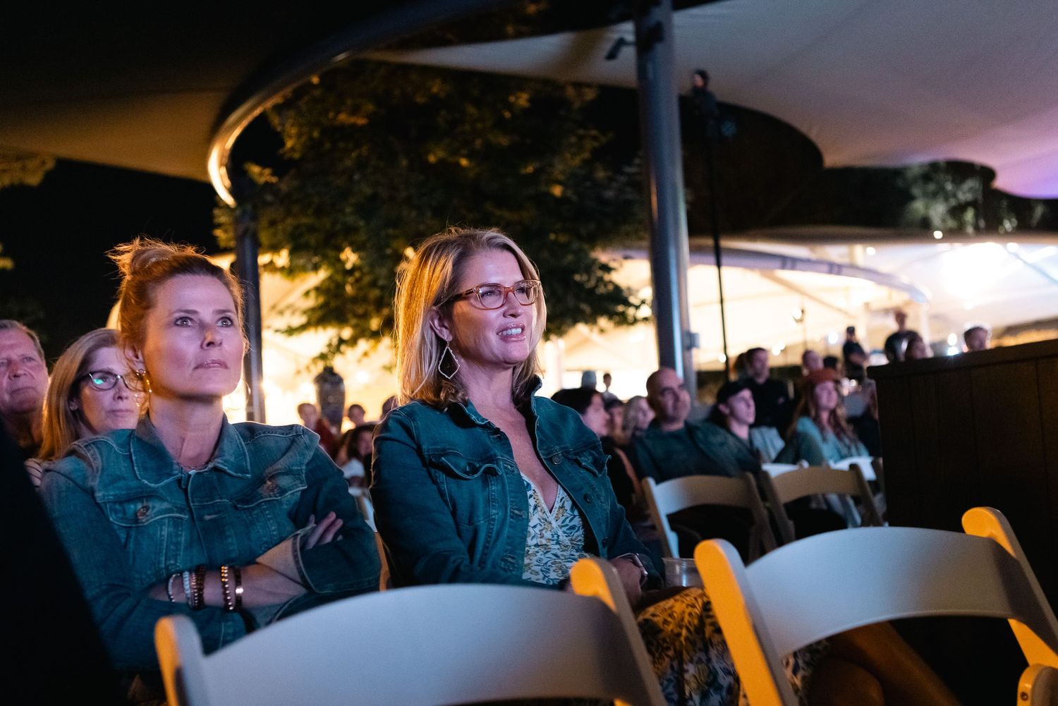 Audience members watching intently during an outdoor evening screening or presentation.