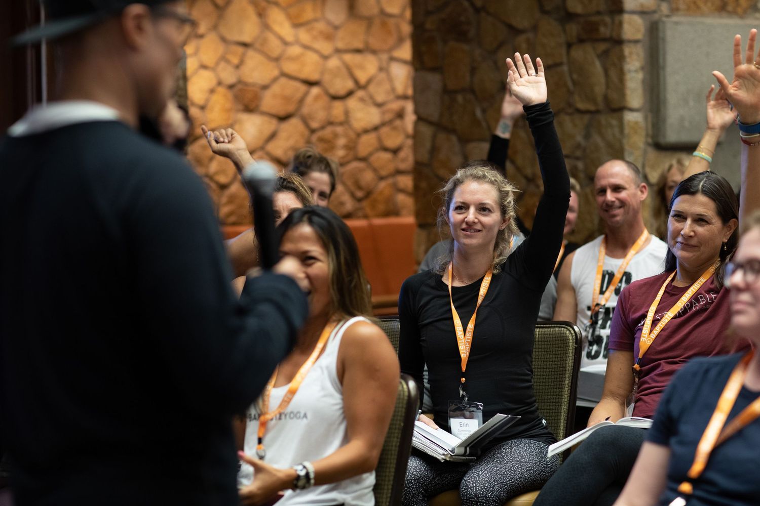 Group of attendees in an indoor exercise class with stone wall background.