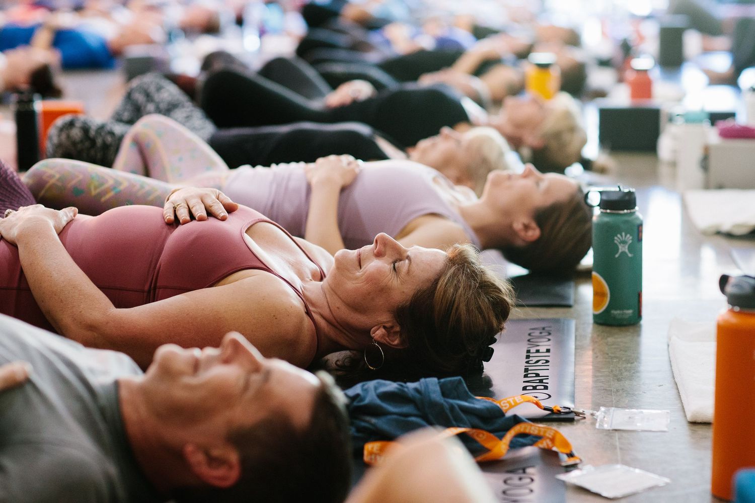 A group of people lying down during a meditation or relaxation session with water bottles nearby.