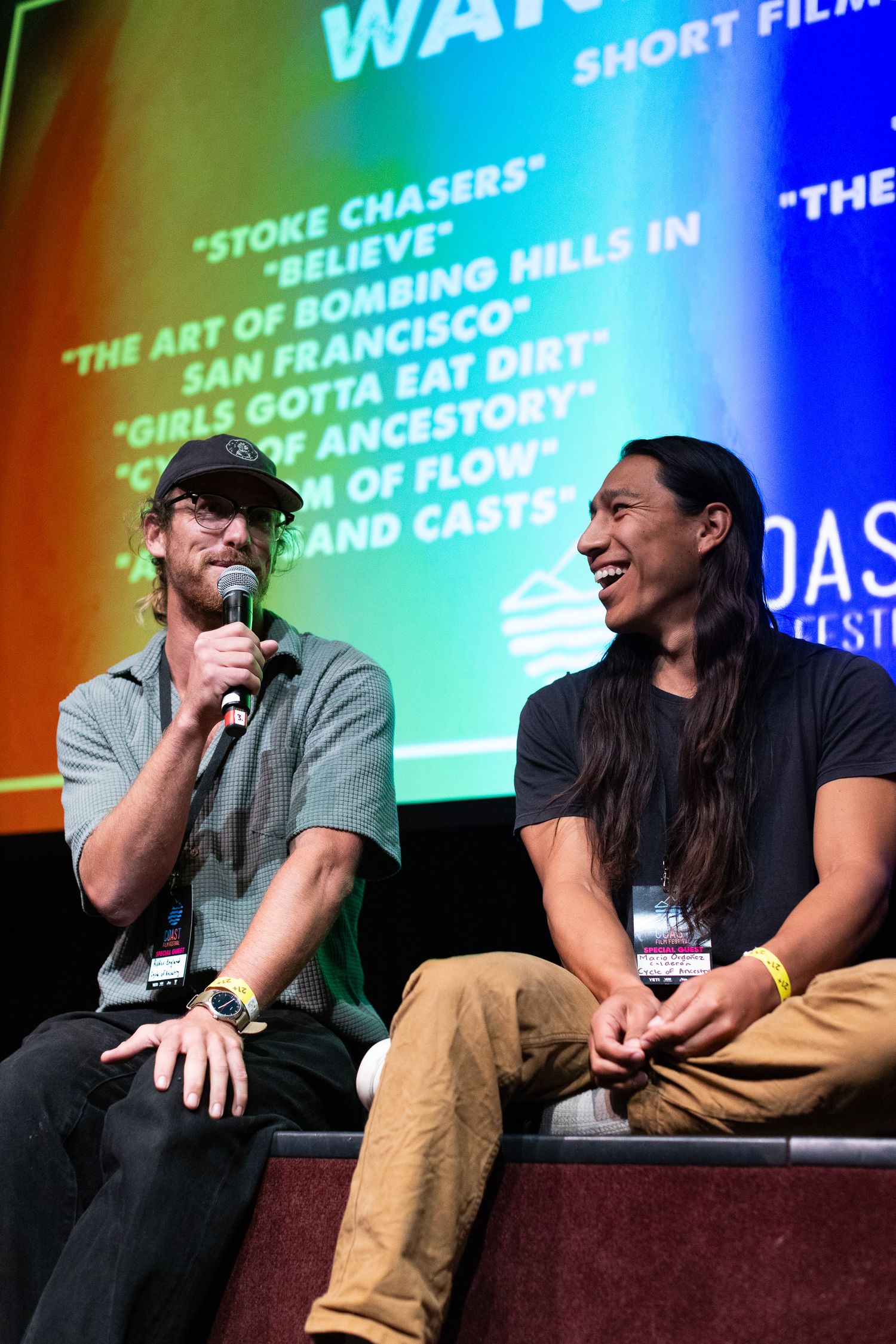 Panel discussion participants seated on stage at a film festival or conference with blue lighting.