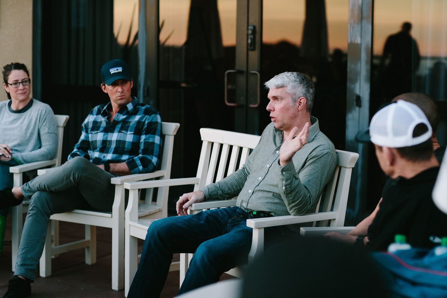 People sitting on outdoor benches at dusk having a conversation.