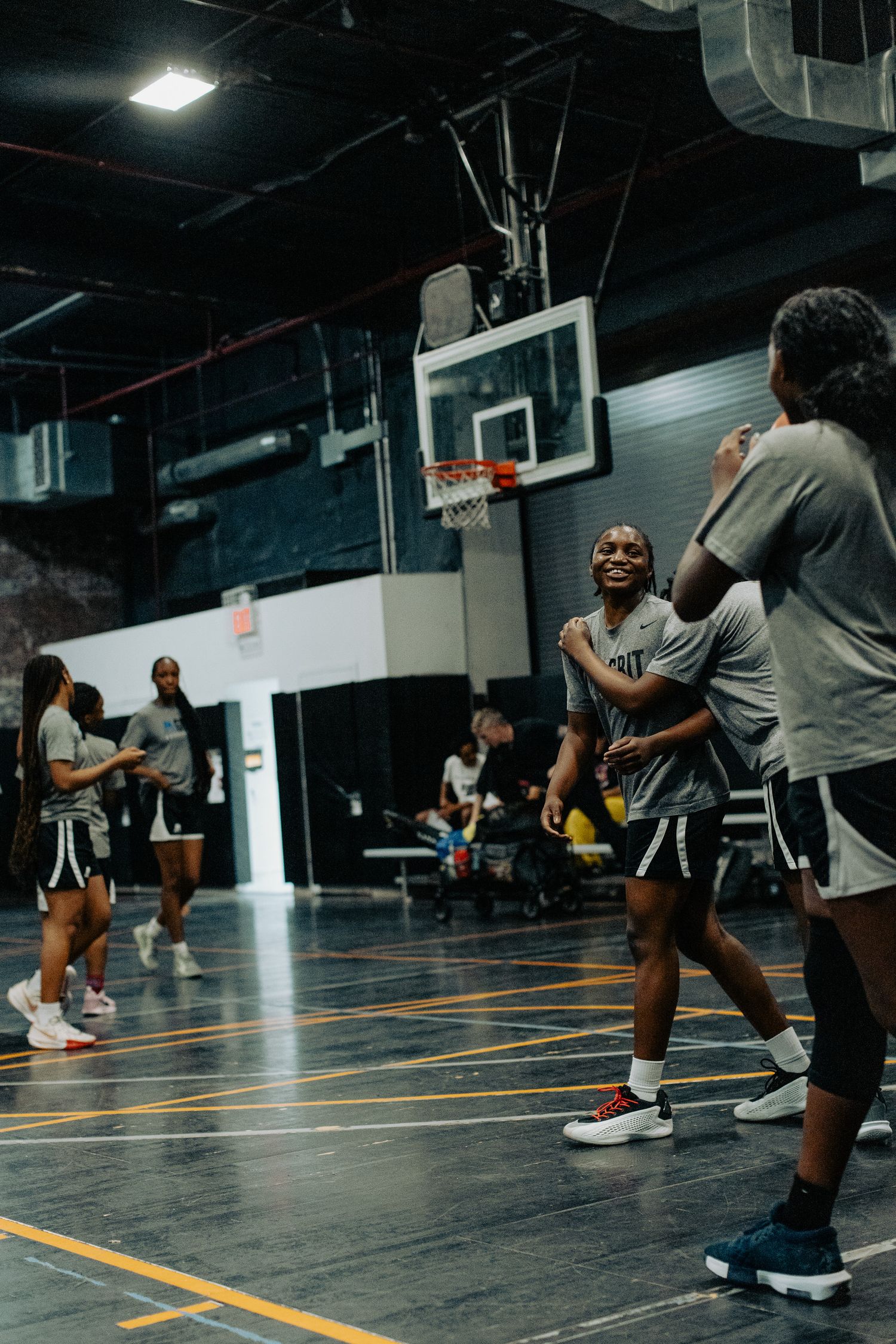 Basketball players practice drills on an indoor court with orange floor markings.