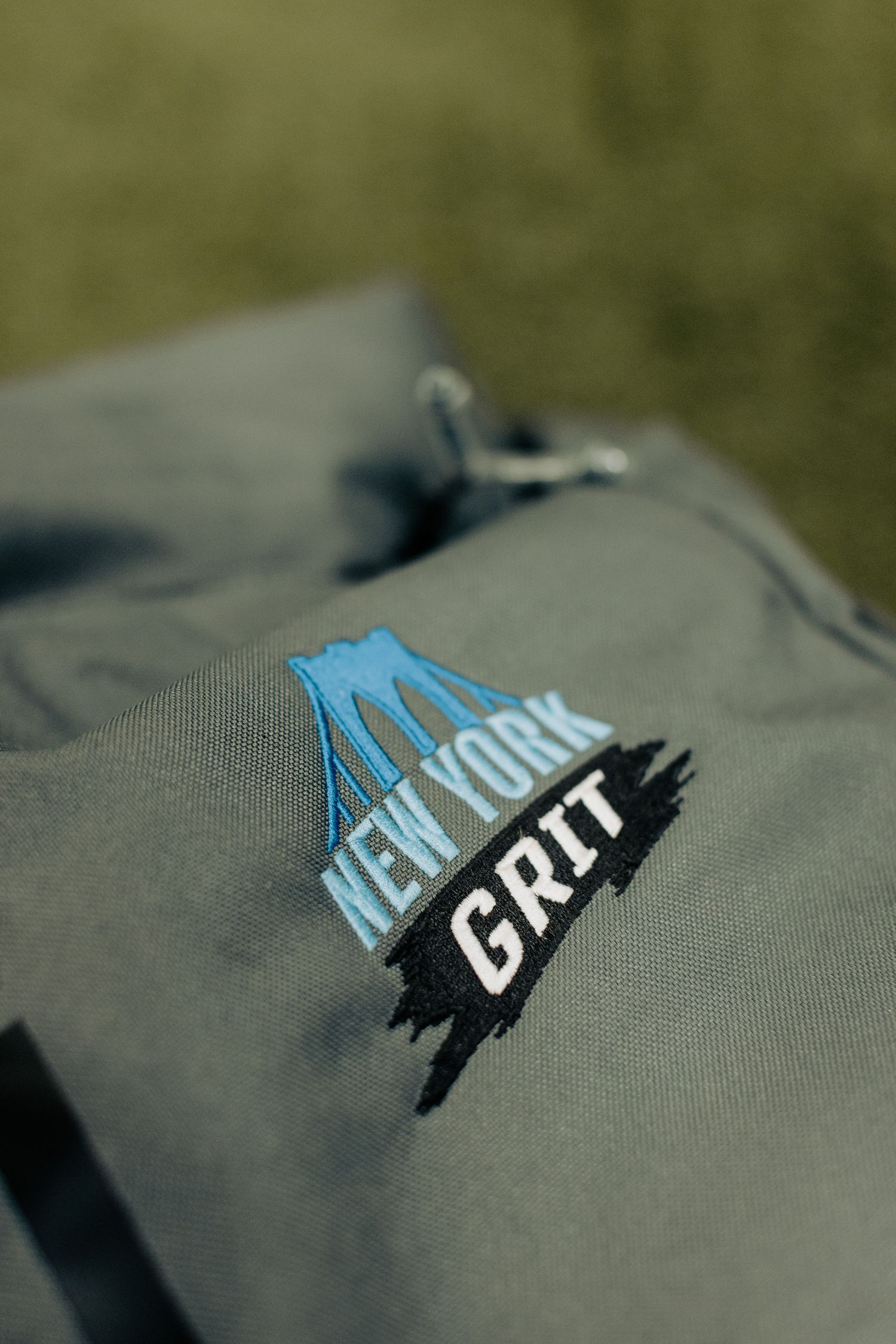 Close-up of New York Grit logo embroidered on grey athletic apparel.