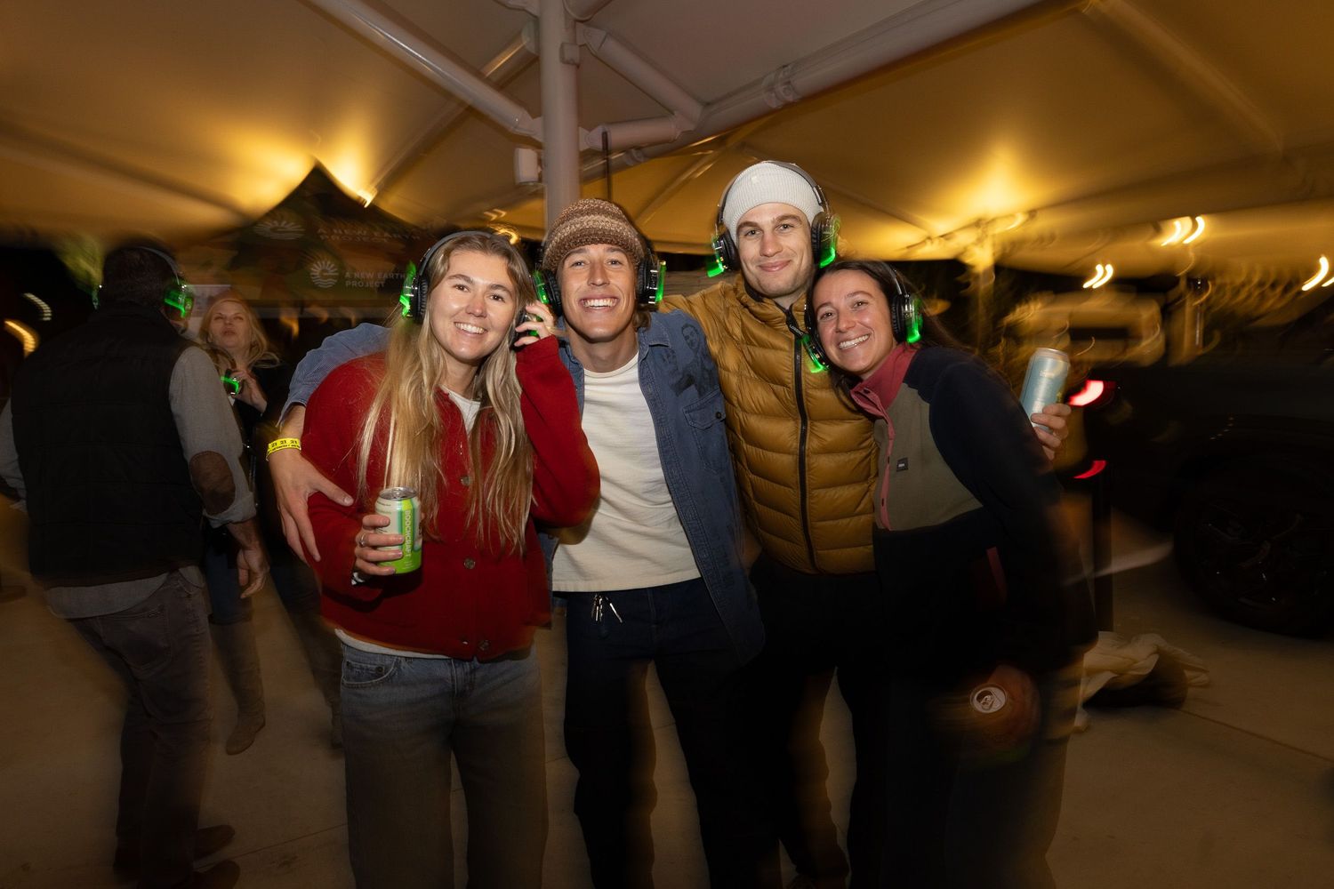People gathering under a warm-lit tent during an evening event with festive lighting.