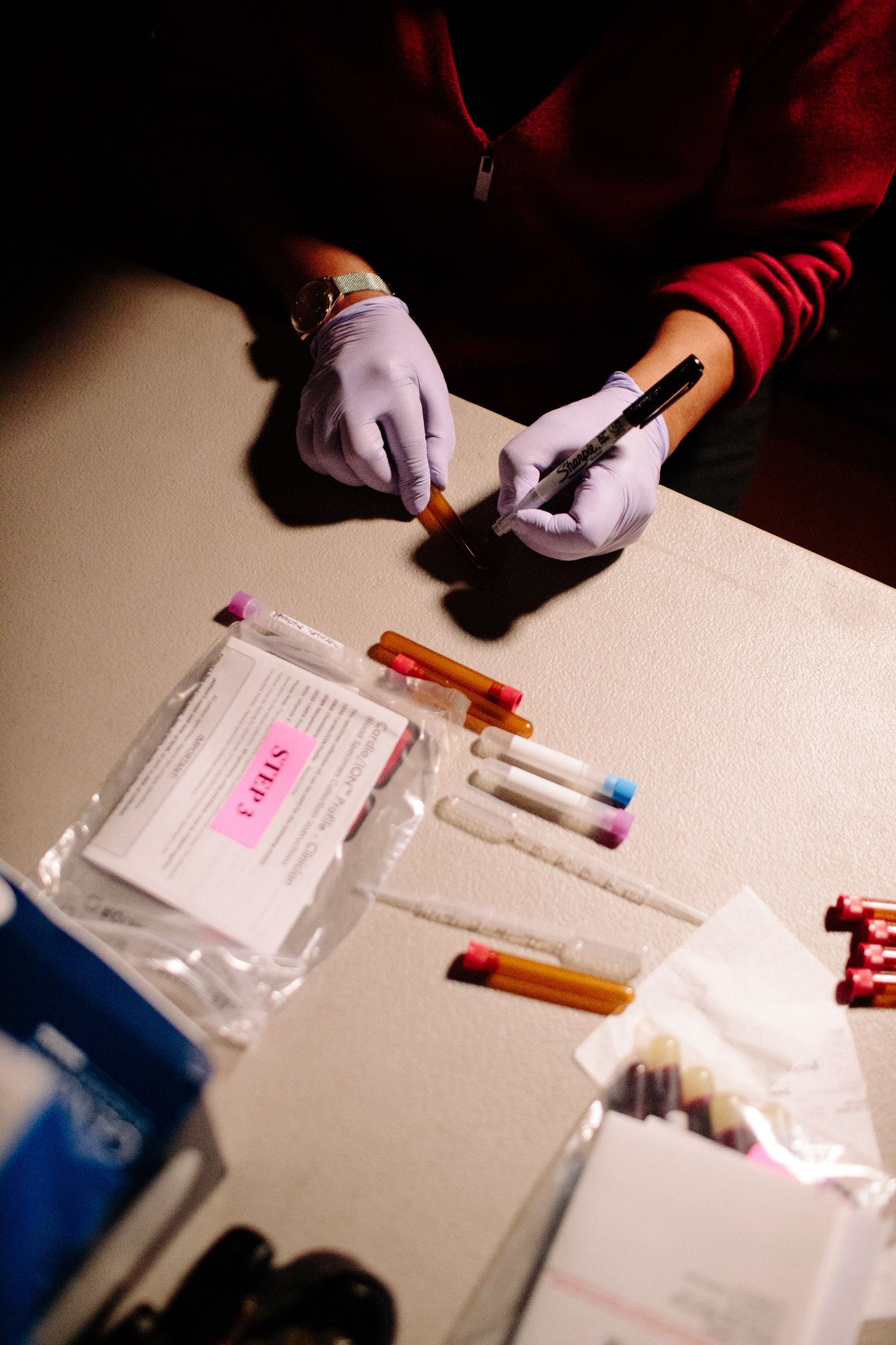 Hands work with colorful materials and documents spread across a white table surface.