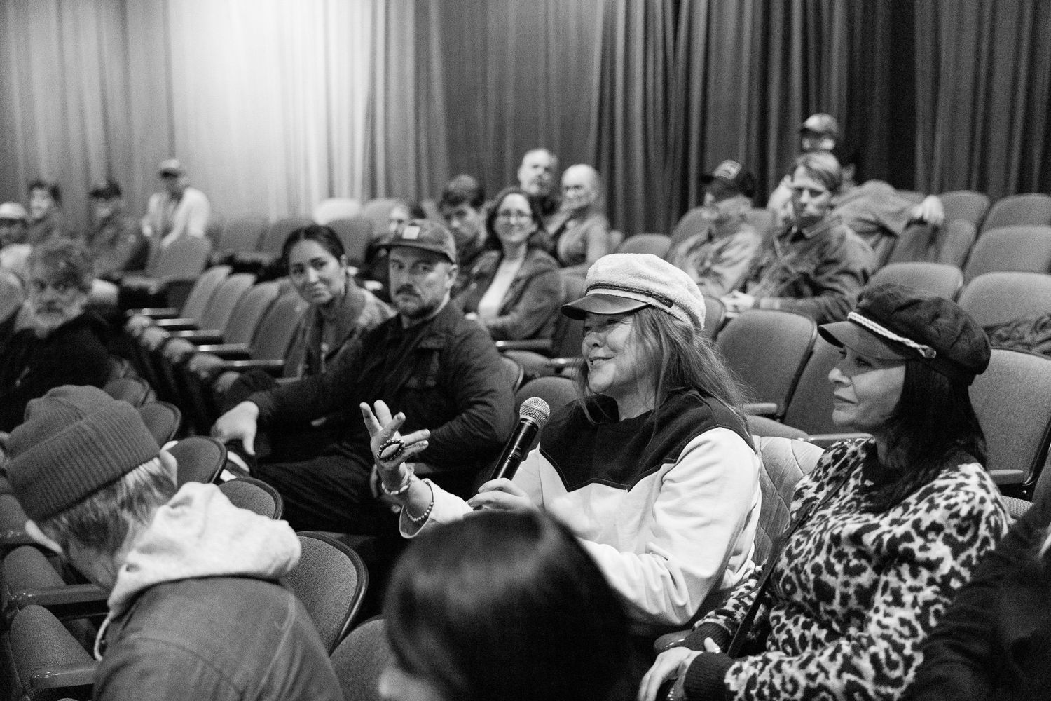 Black and white photo of people taking notes during a presentation in an auditorium.