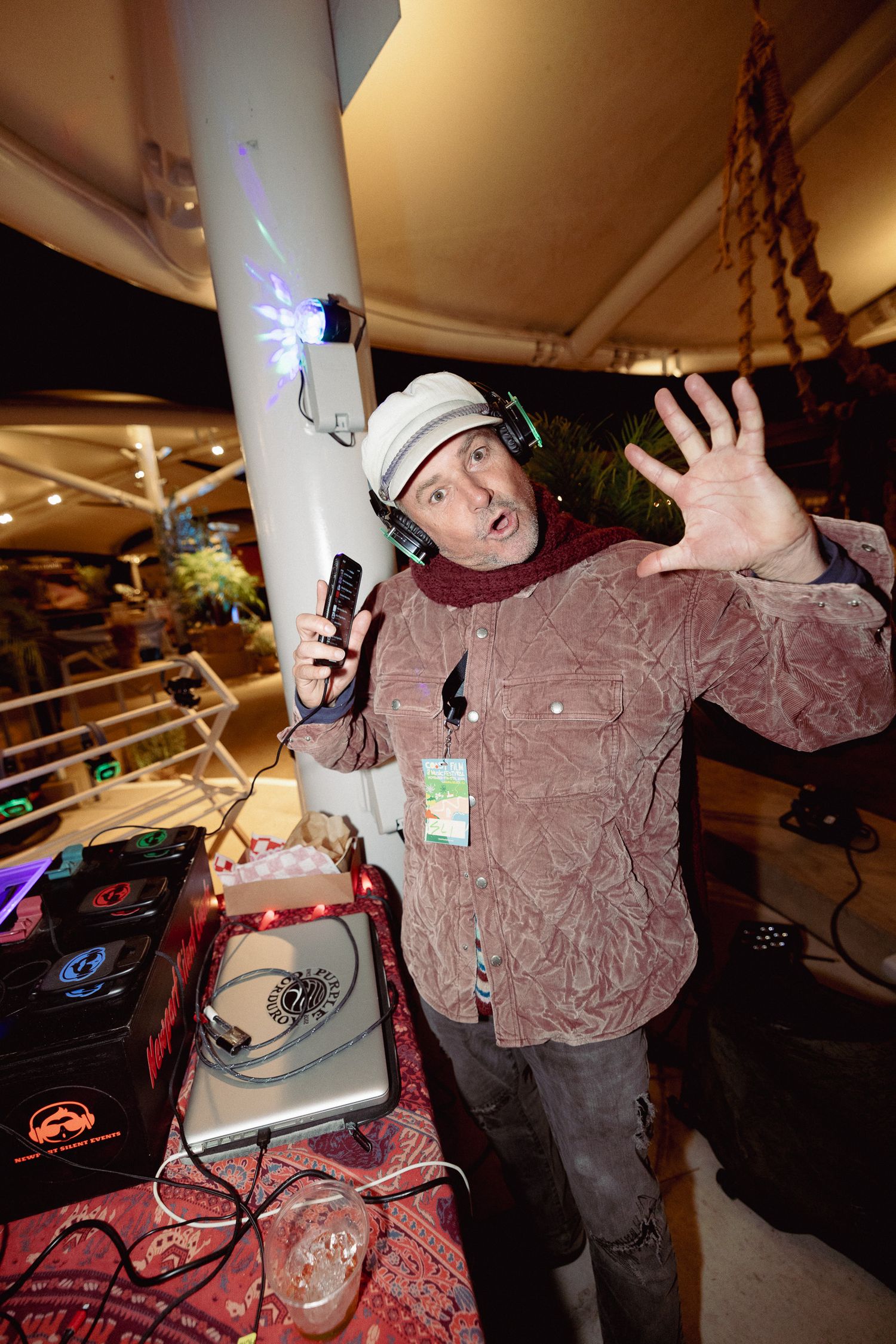 A DJ performs energetically at their booth during a nighttime event.